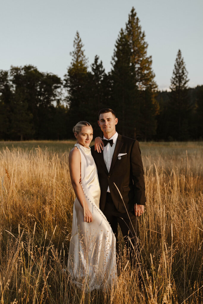 bride and groom facing the sun smiling at the camera at sunset at kinship ranch