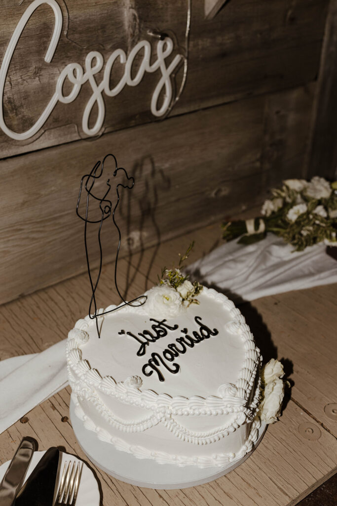 modern white wedding cake with piping and flowers that says "just married" at a summer wedding at kinship ranch