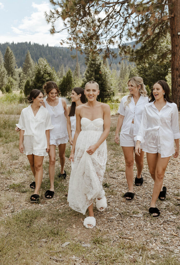 bridesmaids walking and smiling in their pjs outside for a summer wedding at kinship ranch