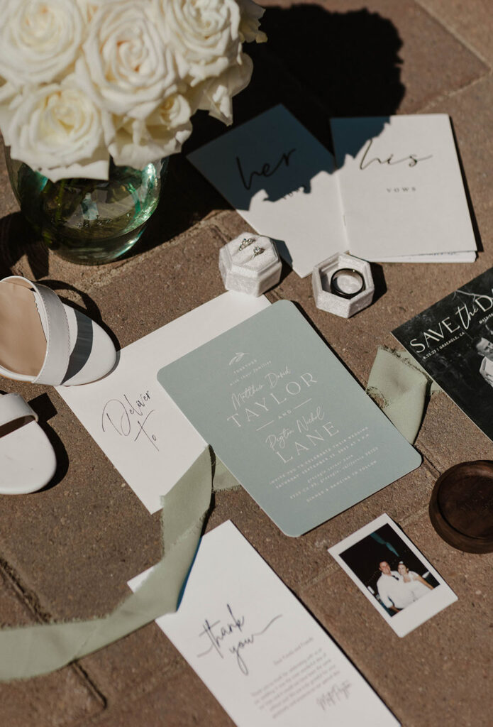 Wedding detail flat lay with announcements and rings on stone at the Corner Barn