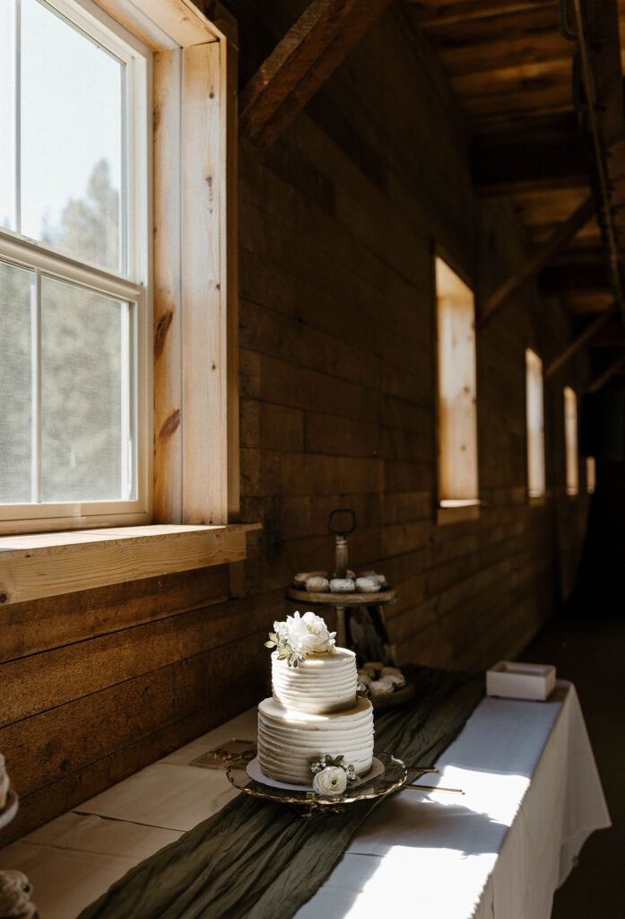 White wedding cake on table with sun rays coming through window at the Corner Barn