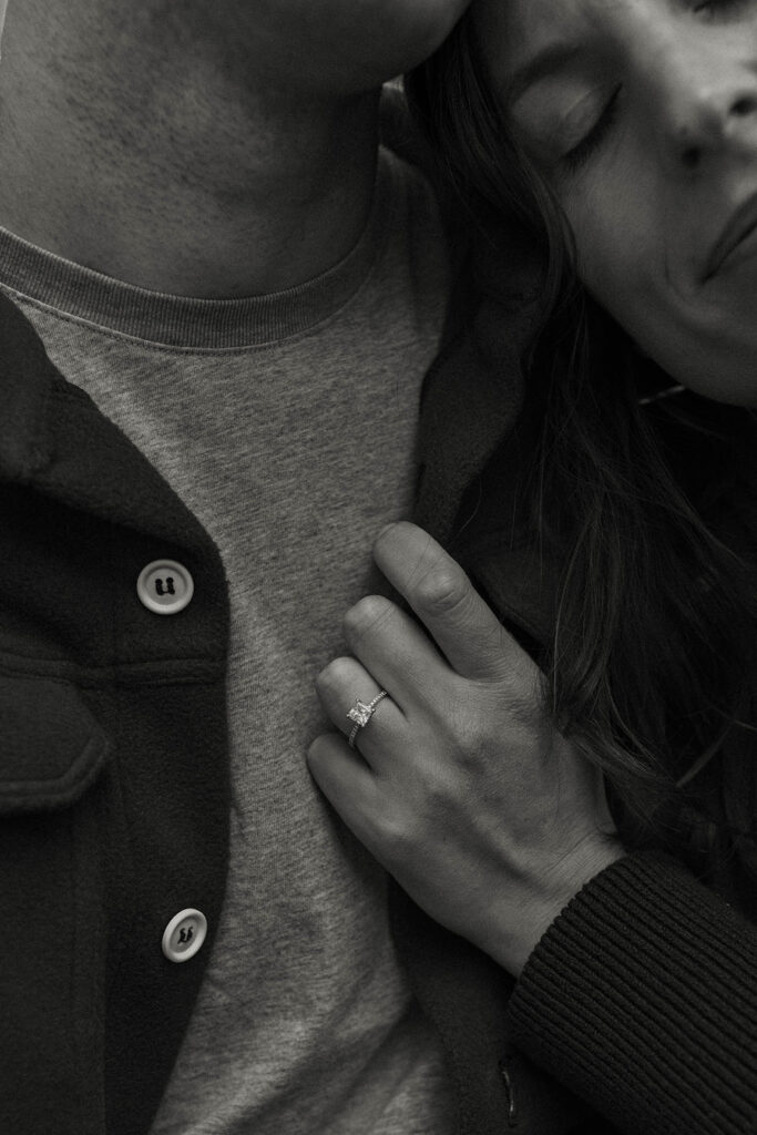 Close up of woman's hand holding fiancé's sweater with engagement ring in Lake Tahoe