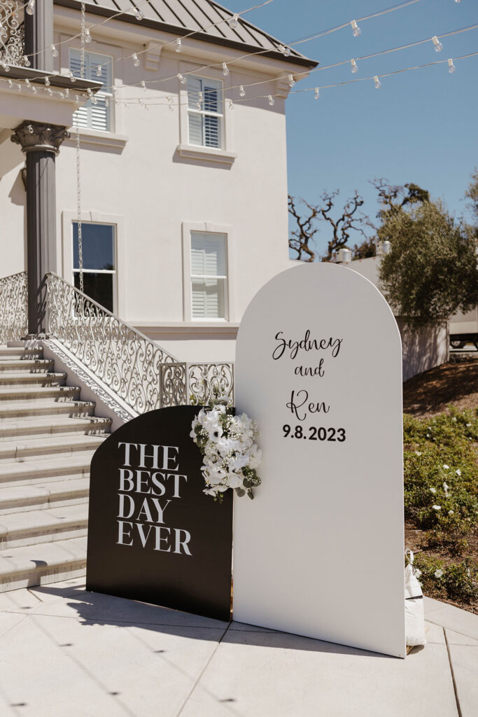 Wedding signs on clean cement with white building and column behind at Willow Heights mansion