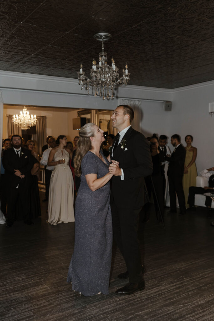 Groom dancing with mom during reception at Willow Heights mansion as guests watch in background