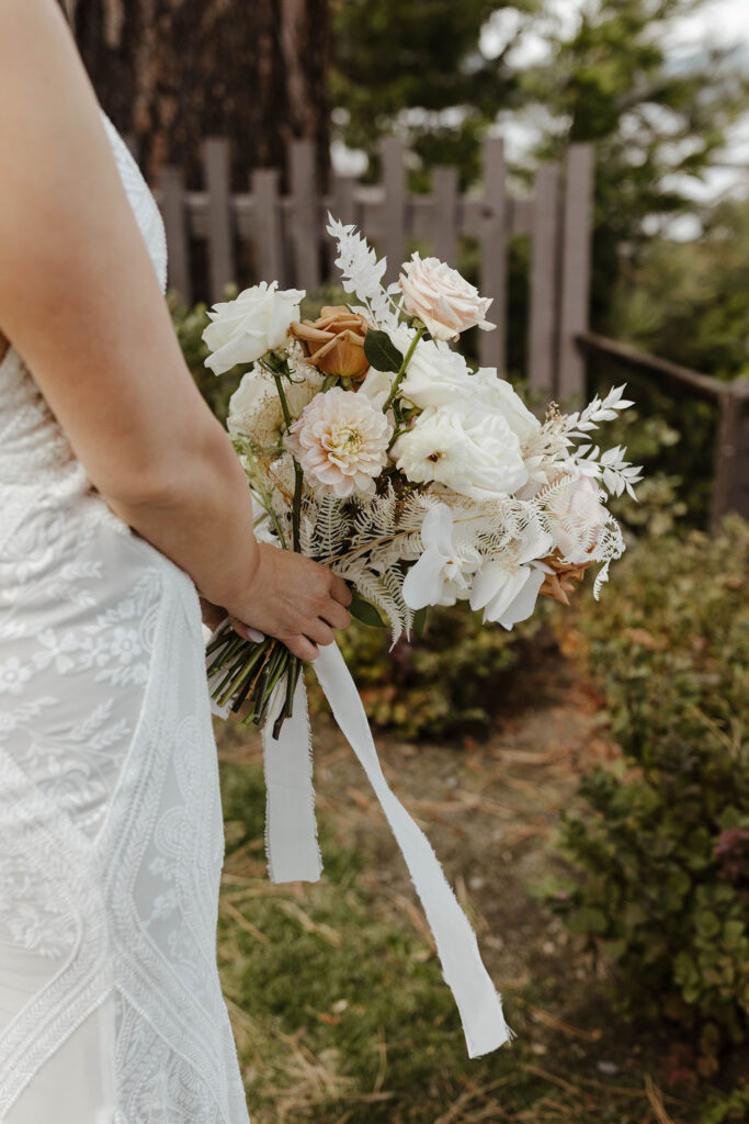 Close up of wedding bride holding floral bouquet with white ribbon hanging down at the PlumpJack Inn