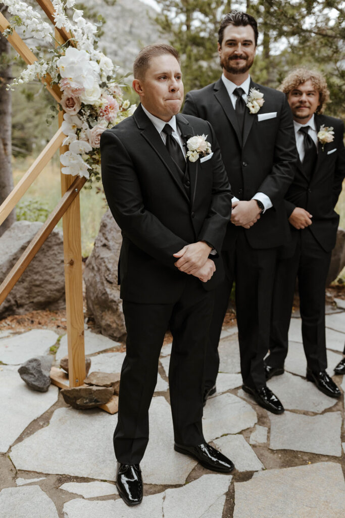 Groom emotional watching bride walking up wedding aisle as groomsmen smile at him during ceremony at the PlumpJack Inn