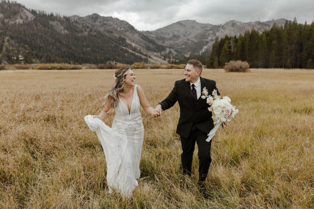 Wedding couple holding hands and smiling at each other while running through golden field together at the PlumpJack Inn