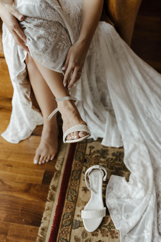 Close up of bride putting on wedding shoes with rug inside at the PlumpJack Inn