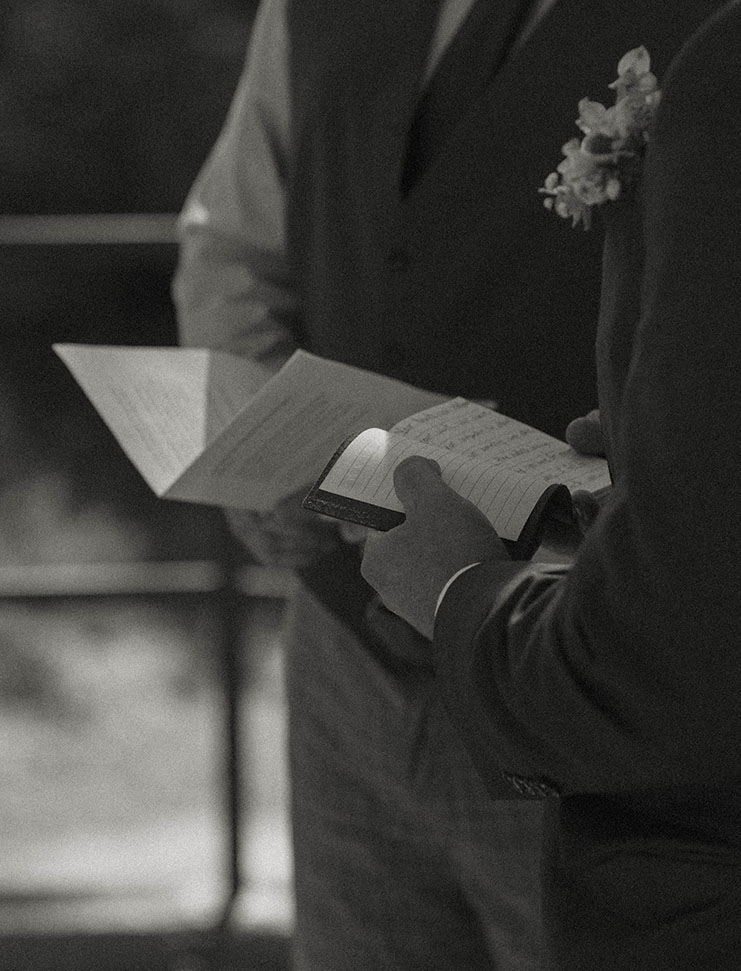 Close up of groom reading wedding vows and officiant holding paper during ceremony at Logan Shoals
