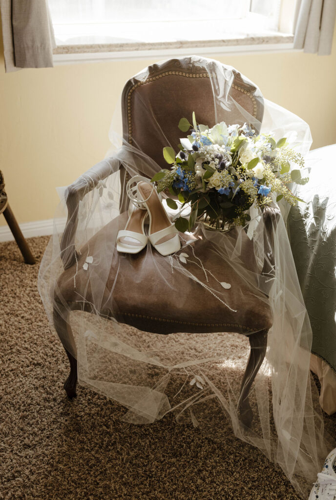 Wedding veil covering chair with shoes and floral bouquet at Logan Shoals