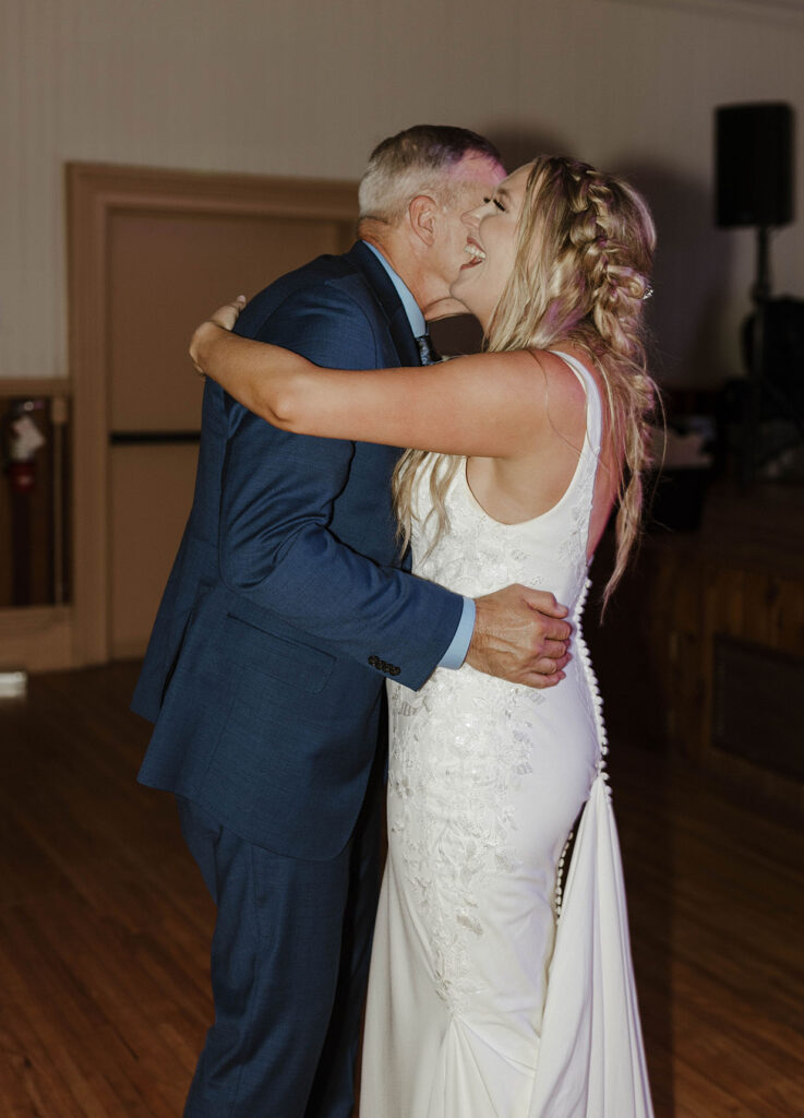 Bride laughing while dancing with her dad during wedding reception at Logan Shoals