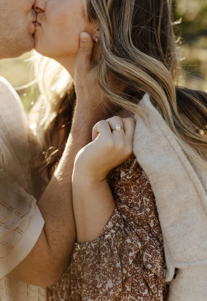 Close up of engagement couple kissing while woman holds jacket over shoulder with engagement ring at Lake Tahoe