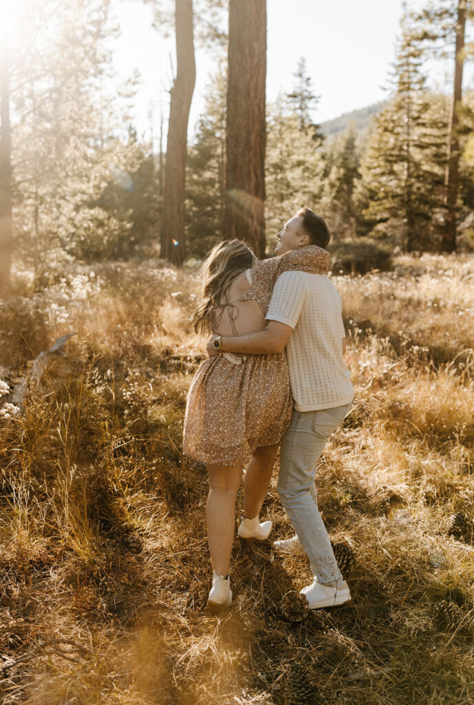 Engagement couple walking through golden field together while holding each other and laughing in Lake Tahoe