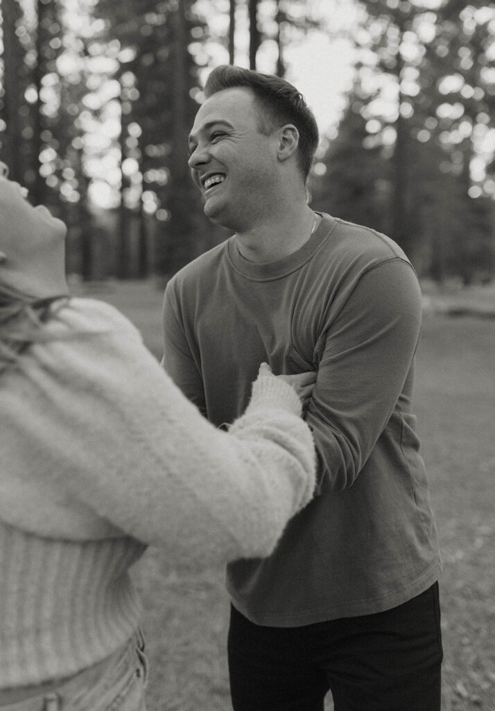 Man laughing while being tickled by fiancé while surrounded by trees in Lake Tahoe