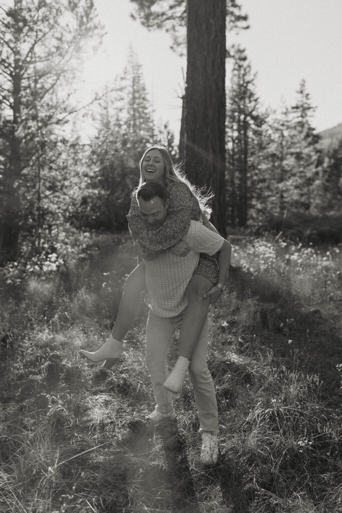 Man giving fiancé a piggyback ride while walking through Lake Tahoe forest together