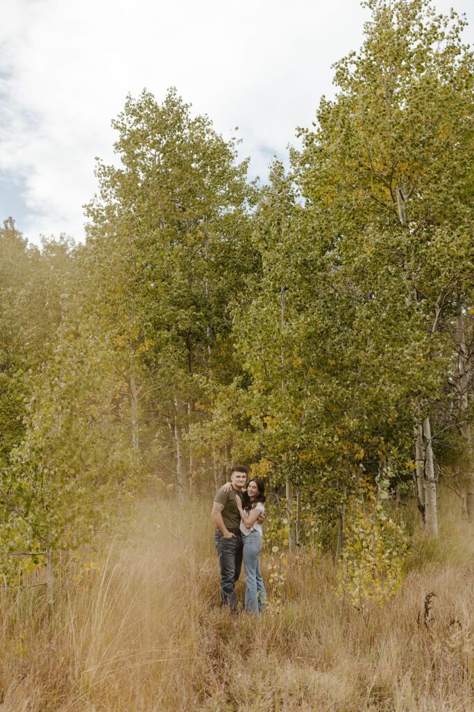 engagement couple smiling in front of aspens in south lake tahoe
