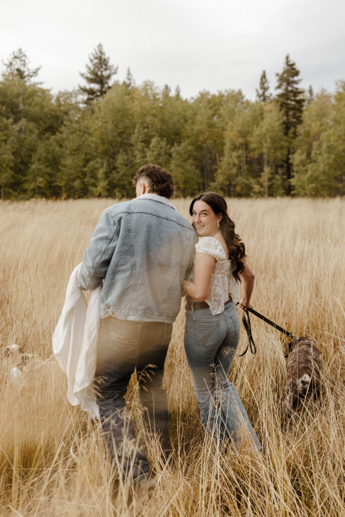 engagement couple walking in a meadow in south lake tahoe with their dogs 
