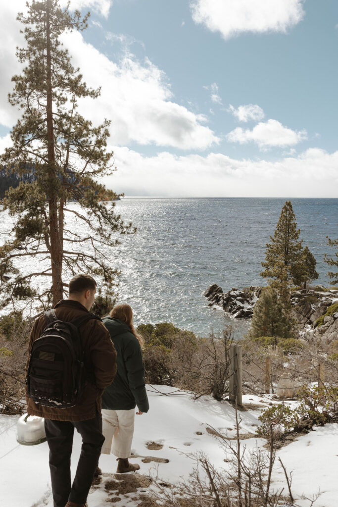 couple hiking in the snow down to secret cove in lake tahoe
