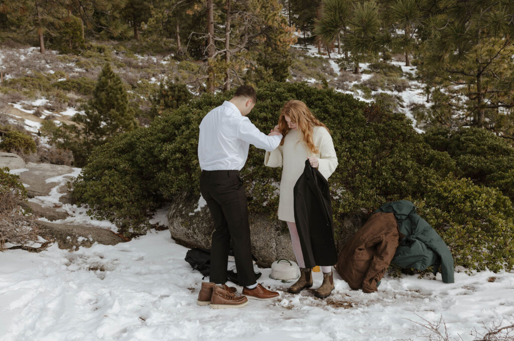 couple getting dressed in the snow in lake tahoe