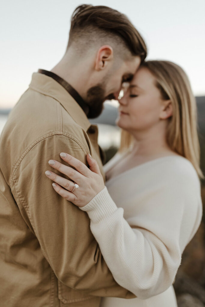 couple hugging at eagle rock with her engagement ring in focus