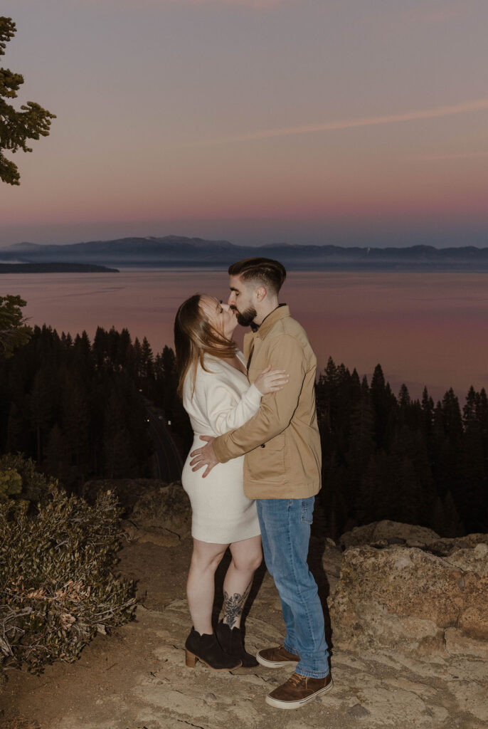 engagement couple kissing at eagle rock overlooking the pink sunset