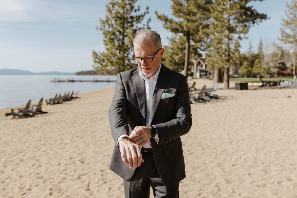 groom adjusting his suit on a beach in lake tahoe