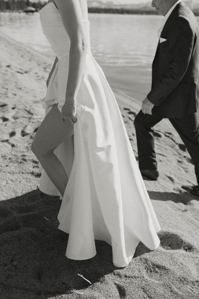 bride holding her dress walking on the beach in lake tahoe