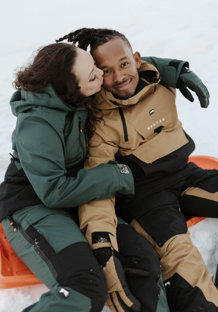 couple sitting on a sled at mount rose meadows
