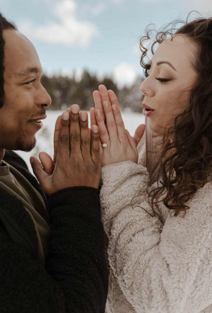engagement couple blowing on their hands in the winter in lake tahoe