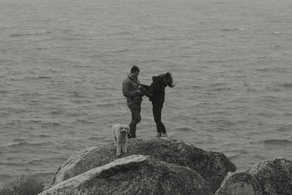 man proposing to woman on a rock in the winter in lake tahoe