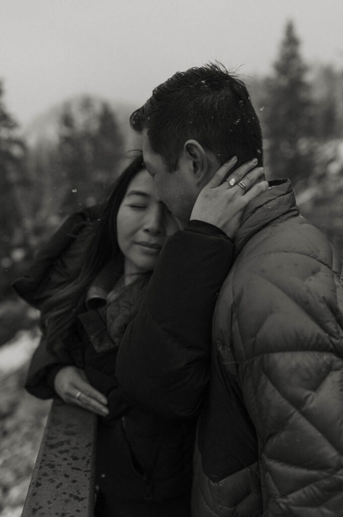 woman holding man in the snow in lake tahoe showing wedding ring