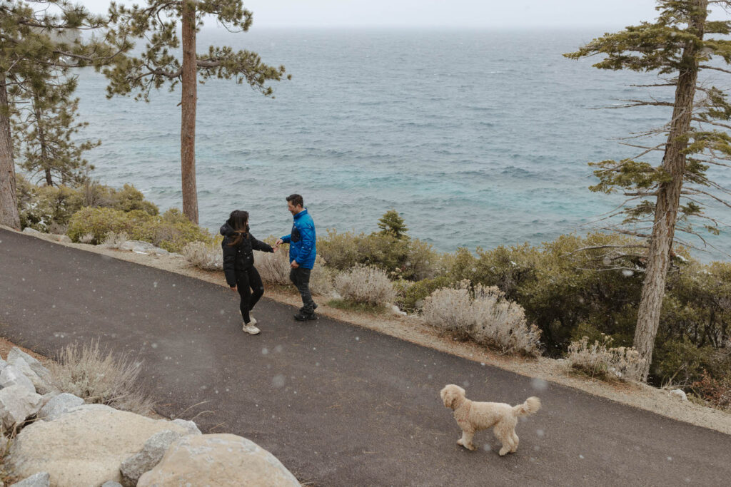 couple walking in on the rim trail lake tahoe while it snows