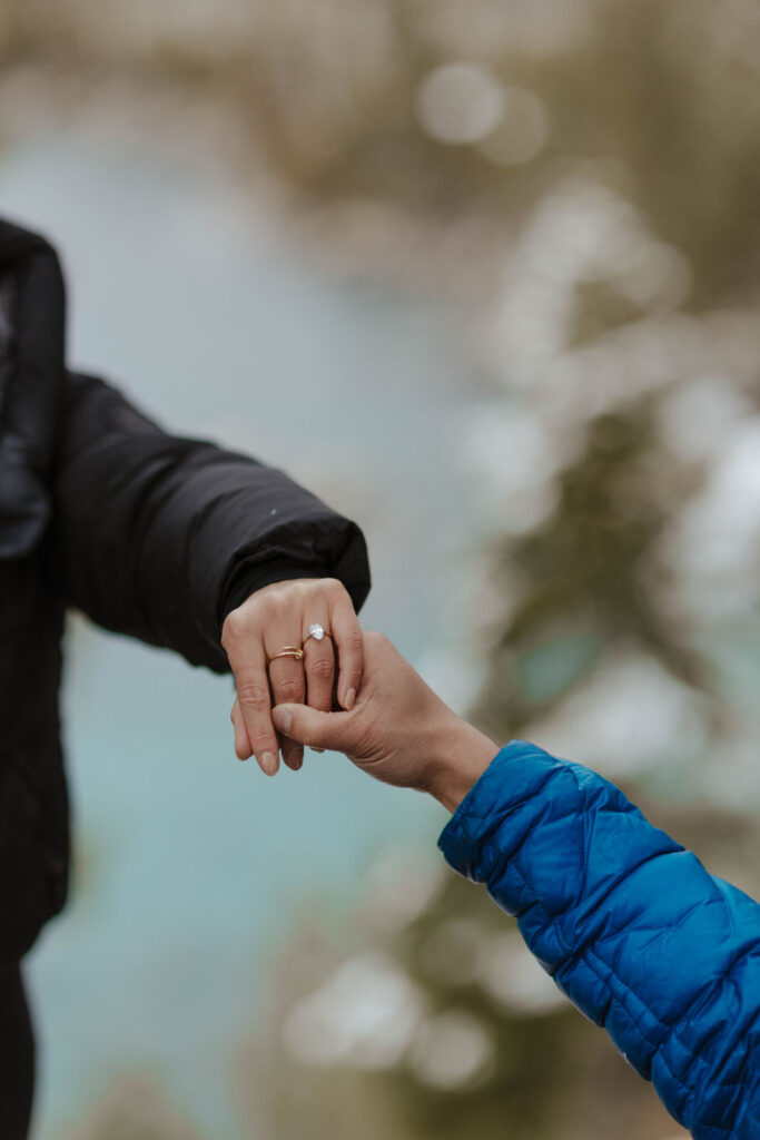 couple holding hands showing engagement ring