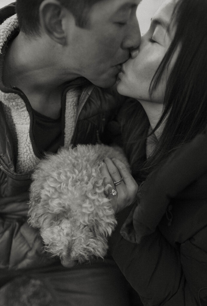 couple kissing and holding their dog