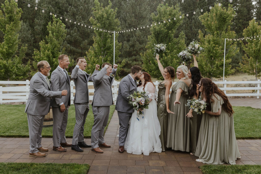 bridal party cheering while the couple kisses at the corner barn in graeagle