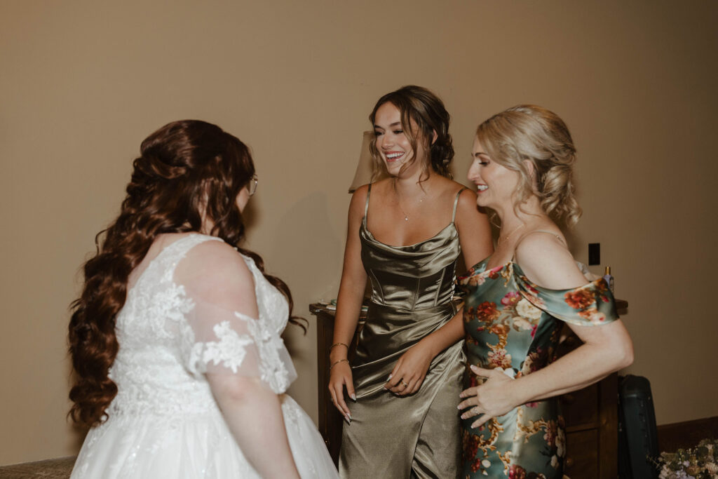 bride and her mom smiling while helping her get ready in graeagle