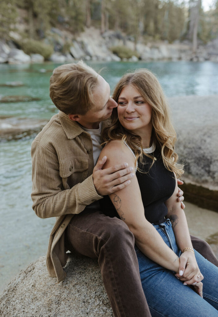 couple sitting on a rock in lake tahoe hugging each other