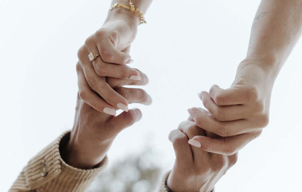 couple holding hands showing engagement ring