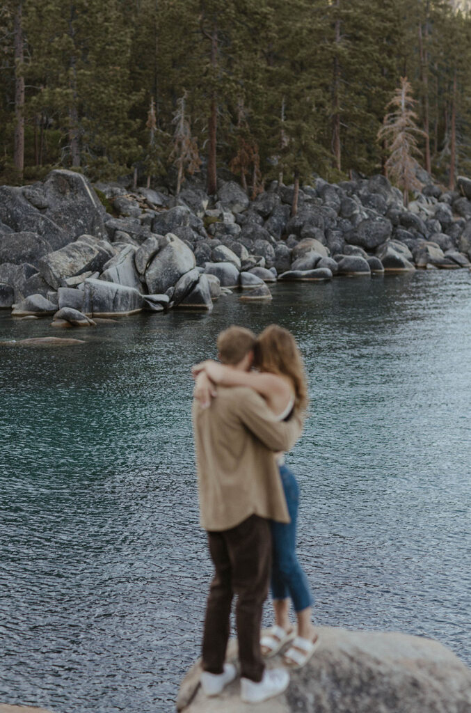 couple hugging while standing on a rock in lake tahoe