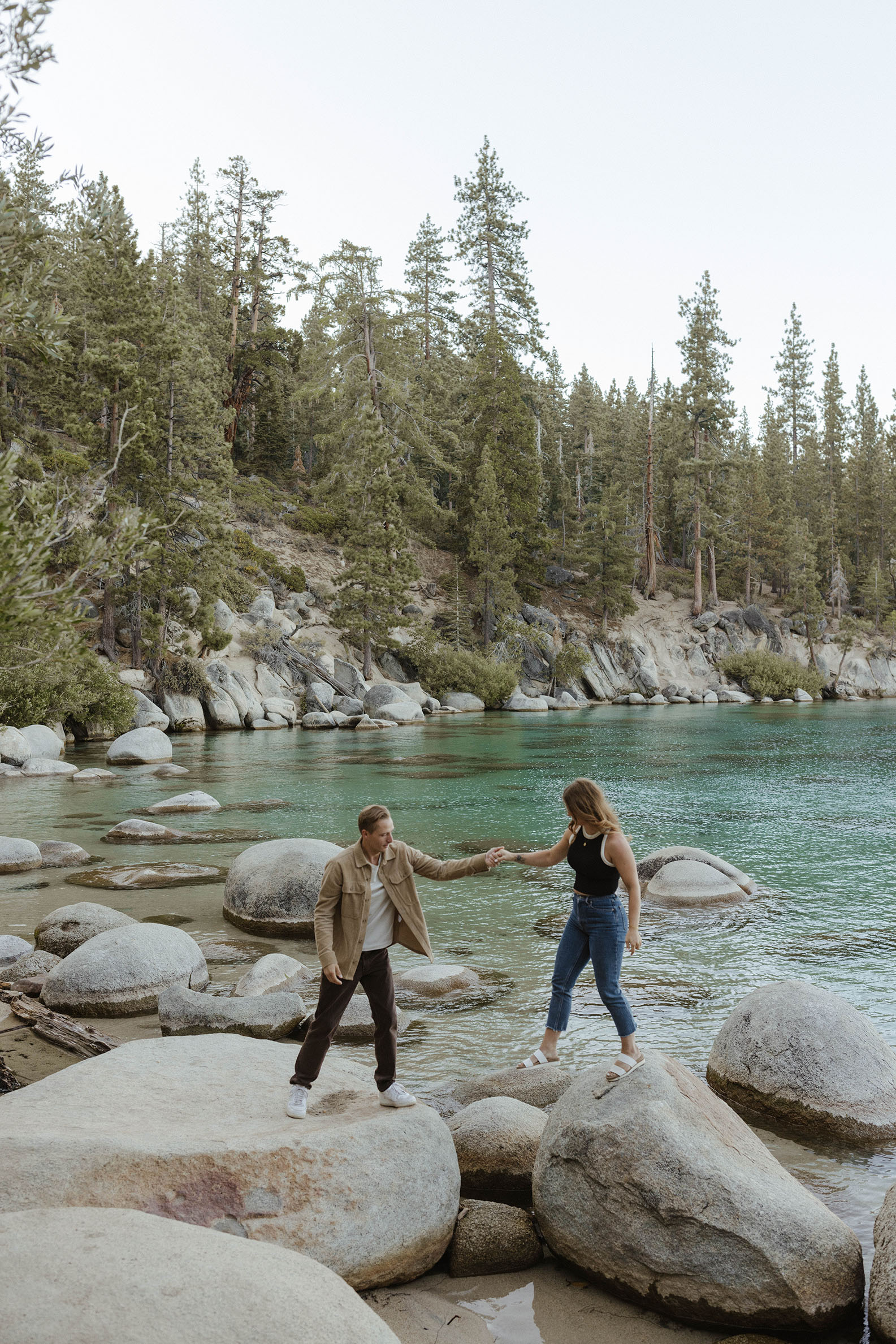 couple helping each walk on rocks in lake tahoe