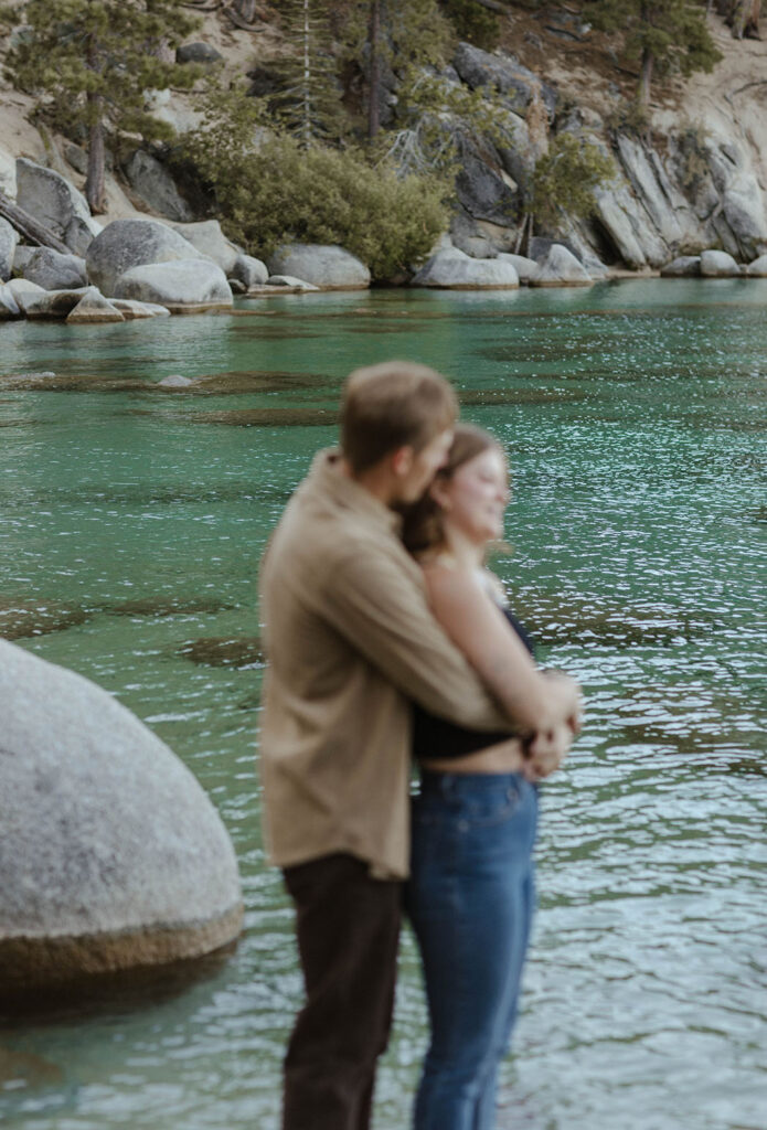 aqua blue water of lake tahoe with couple hugging 