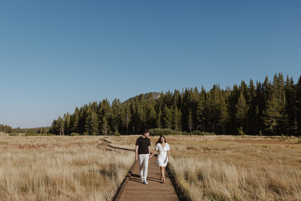 couple walking on wooden board-walk for their fall mount rose meadows engagement photos