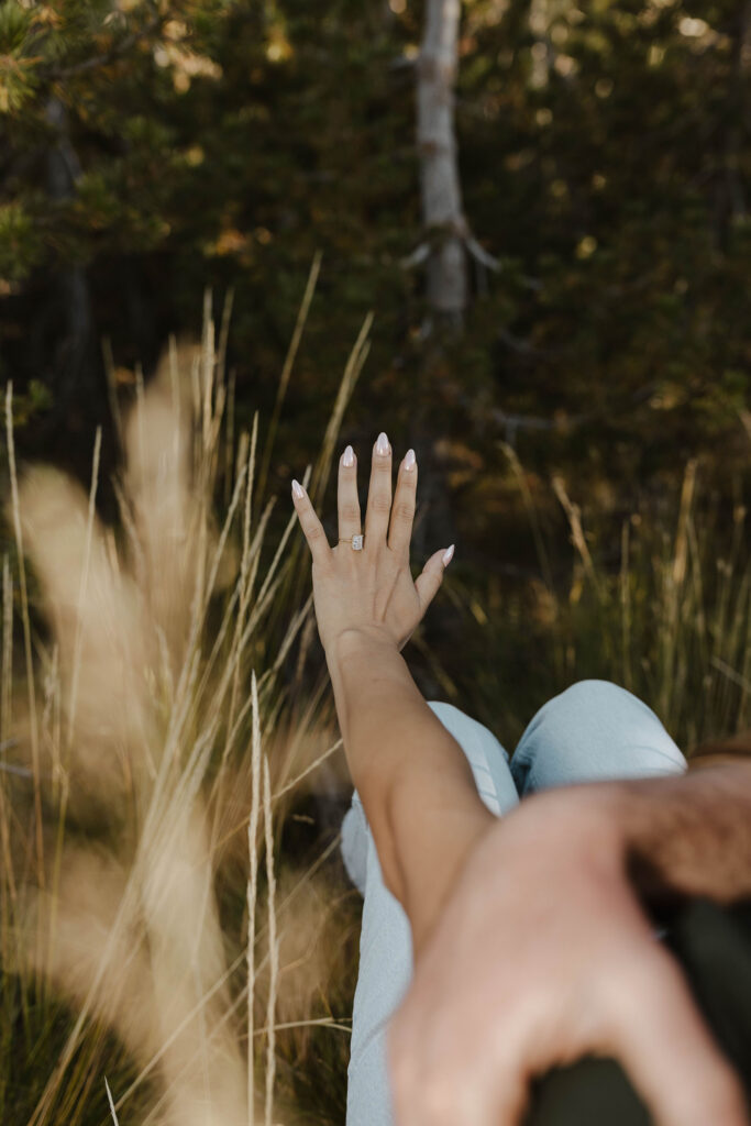 woman looking at her engagement ring while fiance hugs her 
