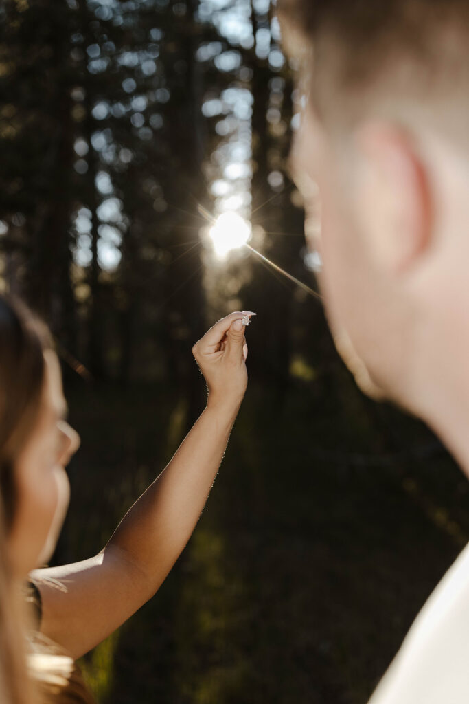 couple holding engagement ring and looking at it during sunset at mount rose meadows