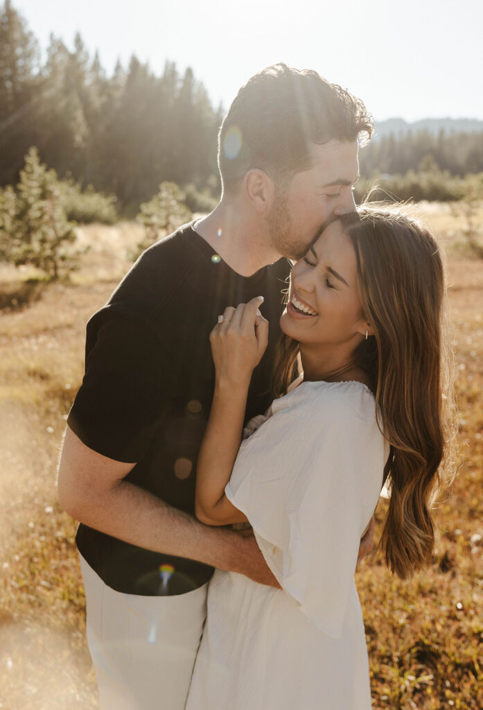 woman laughing while man kisses her in lake tahoe
