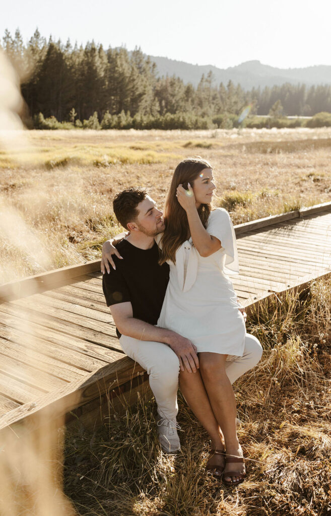 couple sitting on wooden walkway for their engagement photos at mount rose meadows