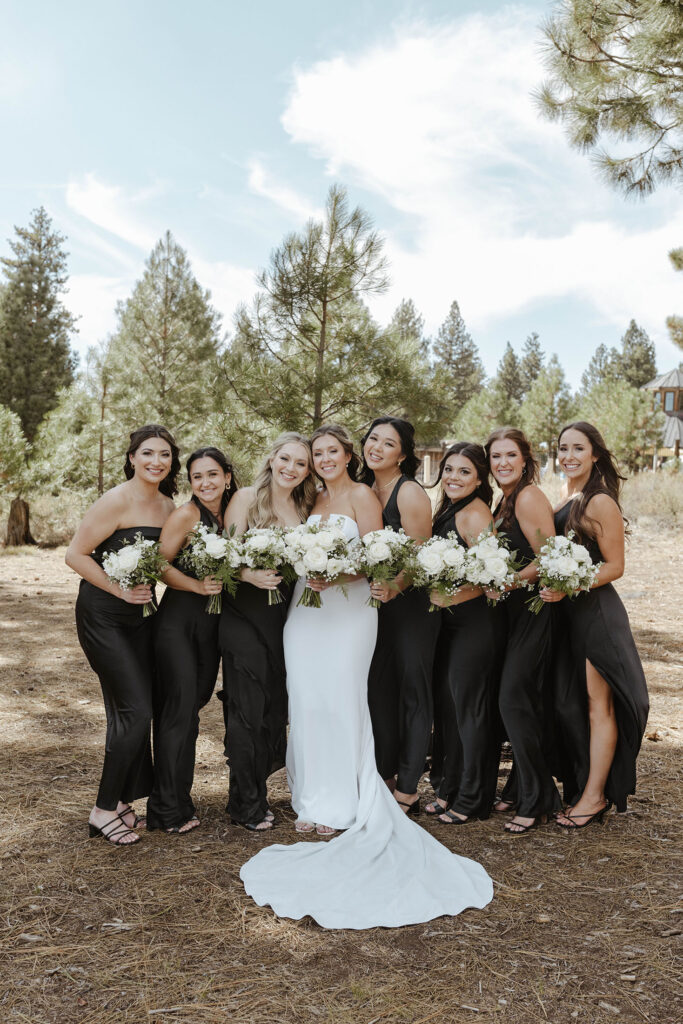 Bride and bridesmaids standing together and smiling at camera while holding floral bouquets at Old Greenwood