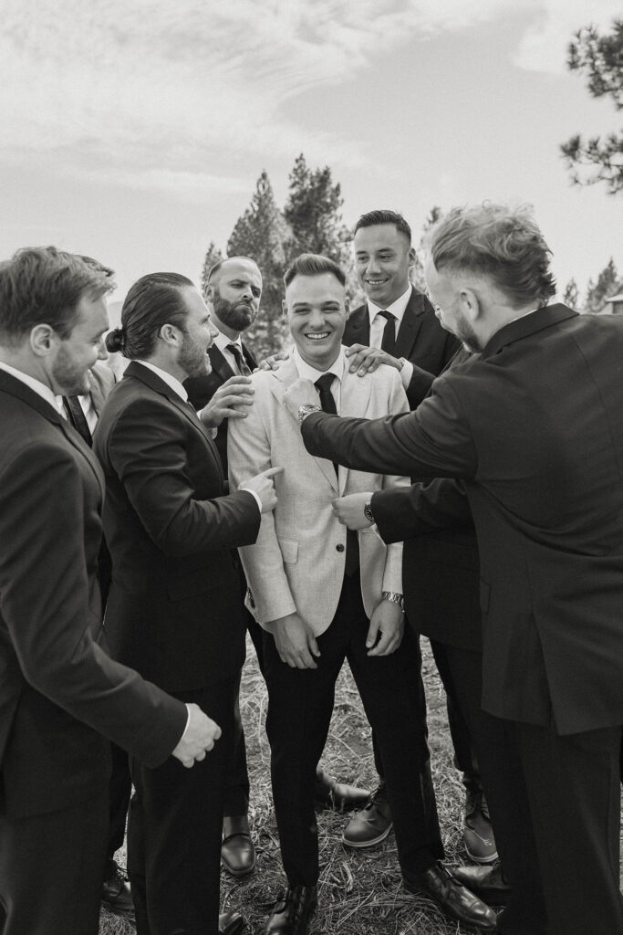 Groomsmen laughing while messing around with groom and fixing his clothes at the Old Greenwood