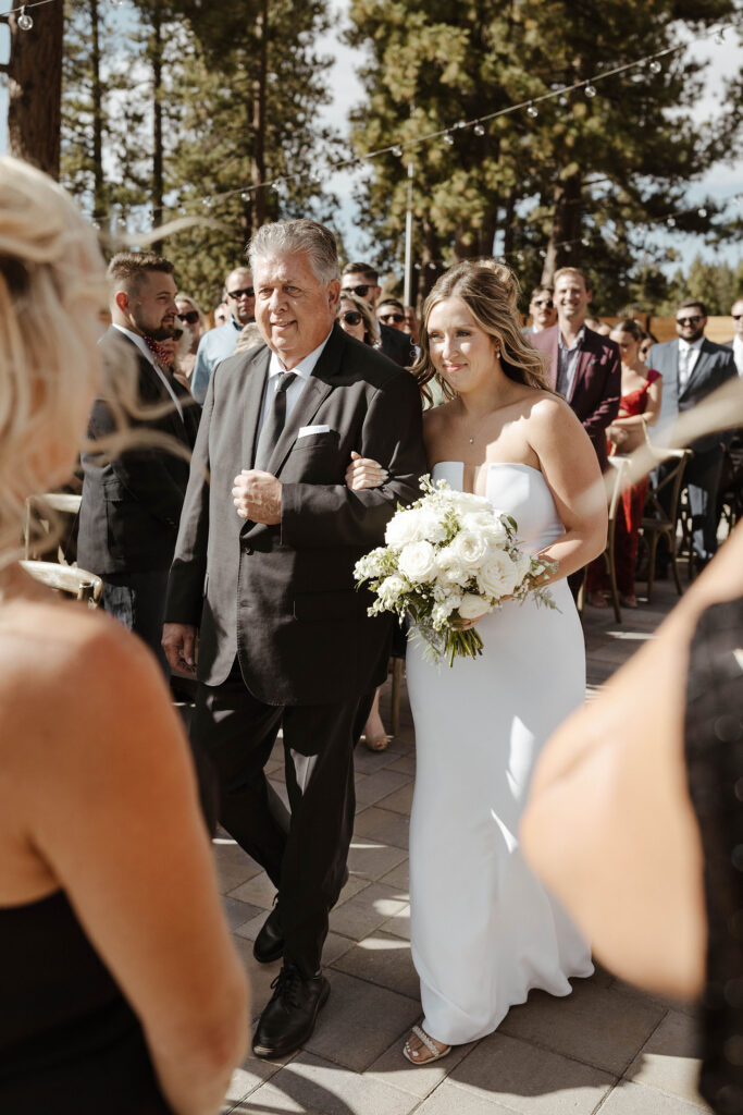 Bride walking down wedding aisle holding Dad's arm during ceremony at Timbers at Old Greenwood