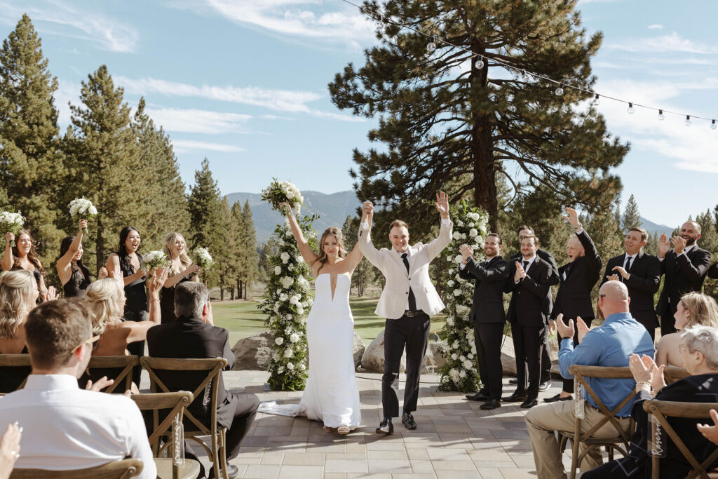 Wedding couple celebrating with hands in air after ceremony at Old Greenwood while walking down the aisle